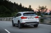 Driving 2019 BMW X1 xDrive28i in Alpine White from a rear left view